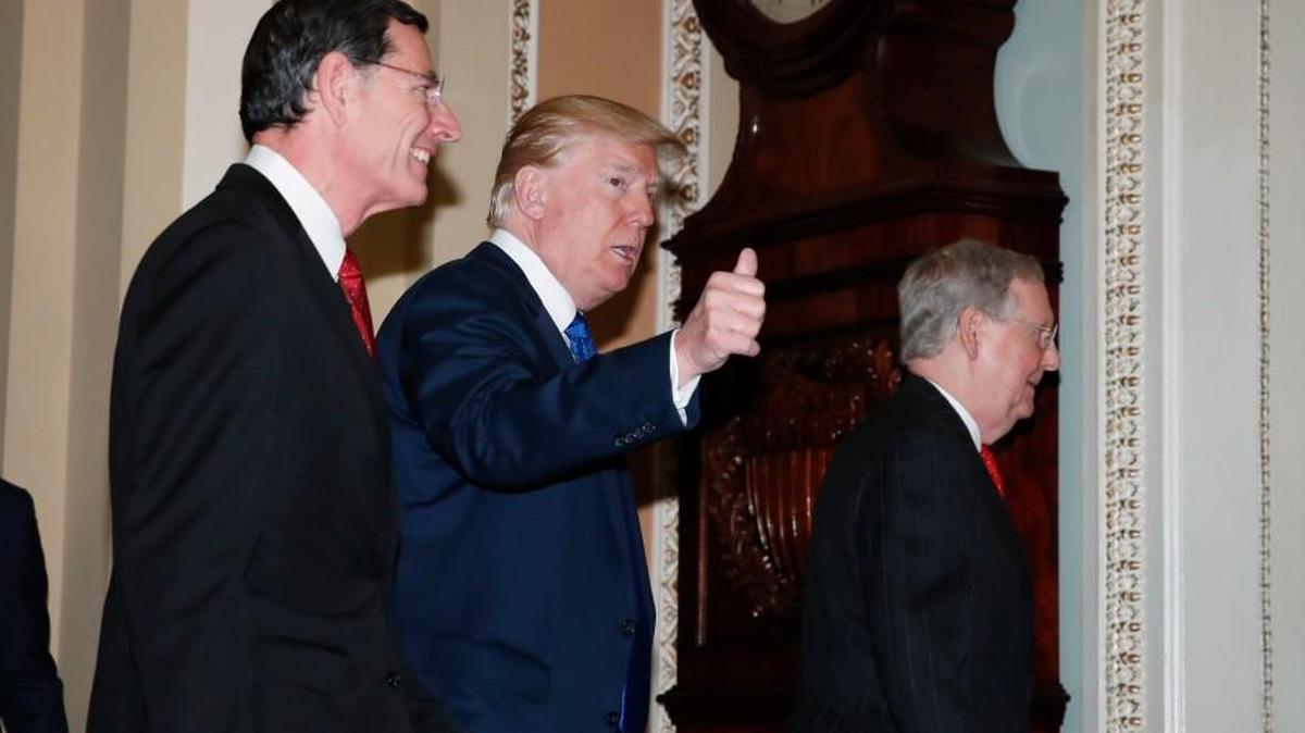 President Donald Trump walks with Senate Majority Leader Mitch McConnell of Ky., right, and Sen. John Barrasso, R-Wy., left, as he arrives to meet with Senate Republicans on Capitol Hill, Tuesday, Nov. 28, 2017.