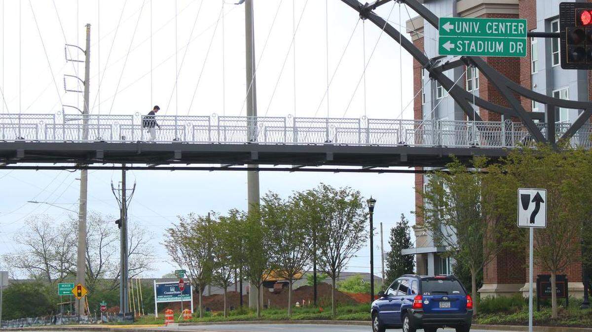 A lone Mercer University student crosses the Mercer Landing pedestrian bridge, which connects Mercer’s main campus in Macon with a private, student-oriented housing development across Mercer University Drive.