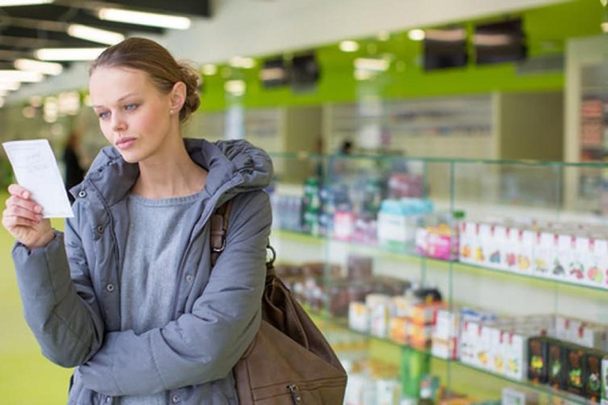 A woman holding a prescription in a pharmacy. Many consumers are abandoning drugstores for online pharmacies.