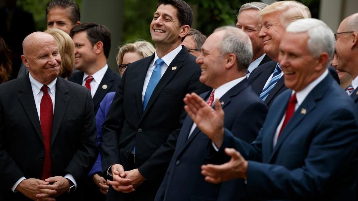 In this May 4, 2017 photo, President Donald Trump, accompanied by GOP House members, cheer for Speaker of the House Rep. Paul Ryan, R-Wis., after the House pushed through a health care bill, in the Rose Garden of the White House in Washington. Members of Congress looking to rewrite former President Barack Obama's Affordable Care Act have a unique perspective, since many of them are signed up for the health care it created.