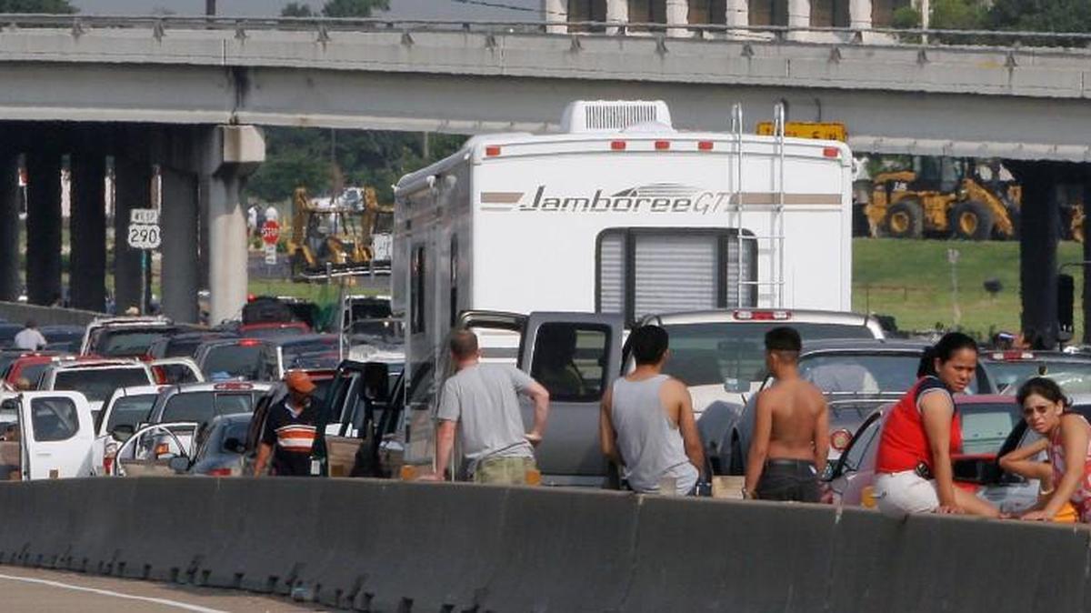 Storm evacuees stand on the side of Highway 290 that became a parking lot as people attempt to flee the approach of Hurricane Rita in Houston on Thursday, Sept. 22, 2005. State and local officials have taken a beating for waiting until millions of Hurricane Rita evacuees had been trapped in gridlock for more than 24 hours before they opened Houston's major highways to one-way outbound traffic. But the Texas Department of Transportation says it wasn't easy to convert 487 miles of highway, including two interstates, to one-way traffic.