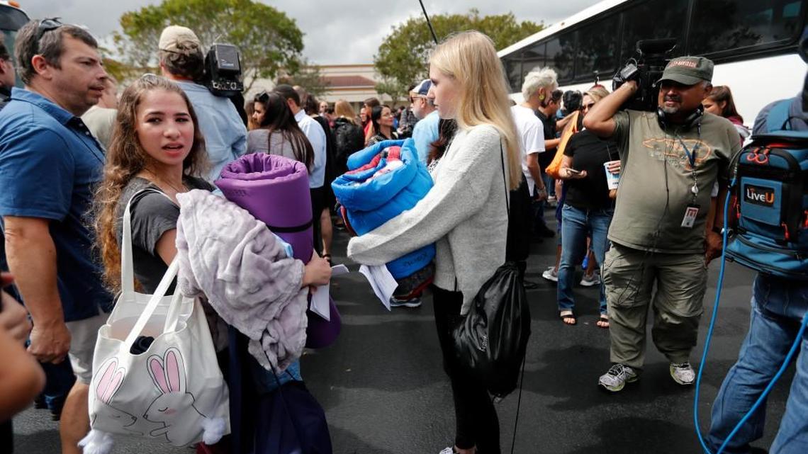 Madyson Kravitz, 16, right, and Melanie Weber, 16, student survivors from Marjory Stoneman Douglas High School, where 17 students and faculty were killed in a mass shooting wait to board buses in Parkland, Fla., on Tuesday to rally outside the state capitol and talk to legislators about gun control reform.
