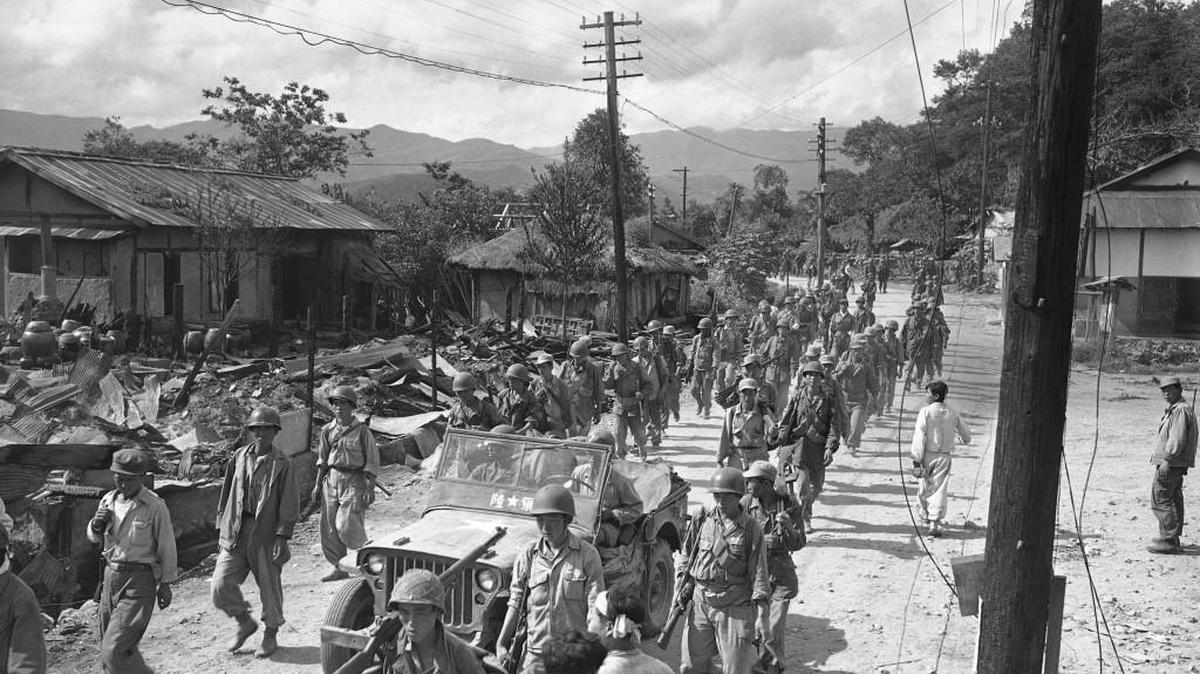 Republic of Korea troops stream through Yangyank, seven miles north of the 38th parallel in pursuit of retreating North Koreans, Oct. 4, 1950. This contingent was the first to cross the mythical border at the 38th into North Korea.