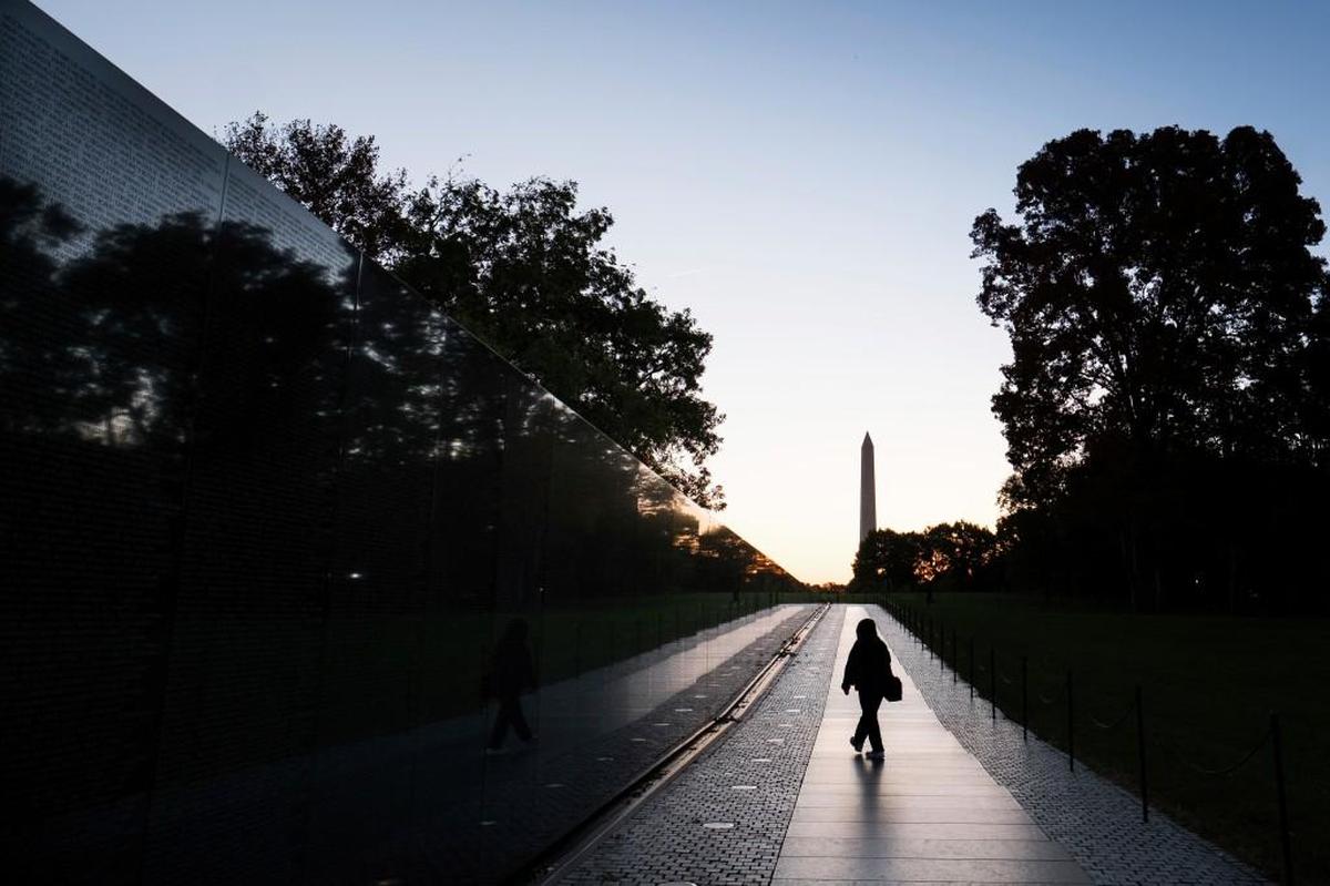 A visitor walks along a wall of names at the Vietnam War Memorial early in the morning, Tuesday, Oct. 25, 2016, in Washington.