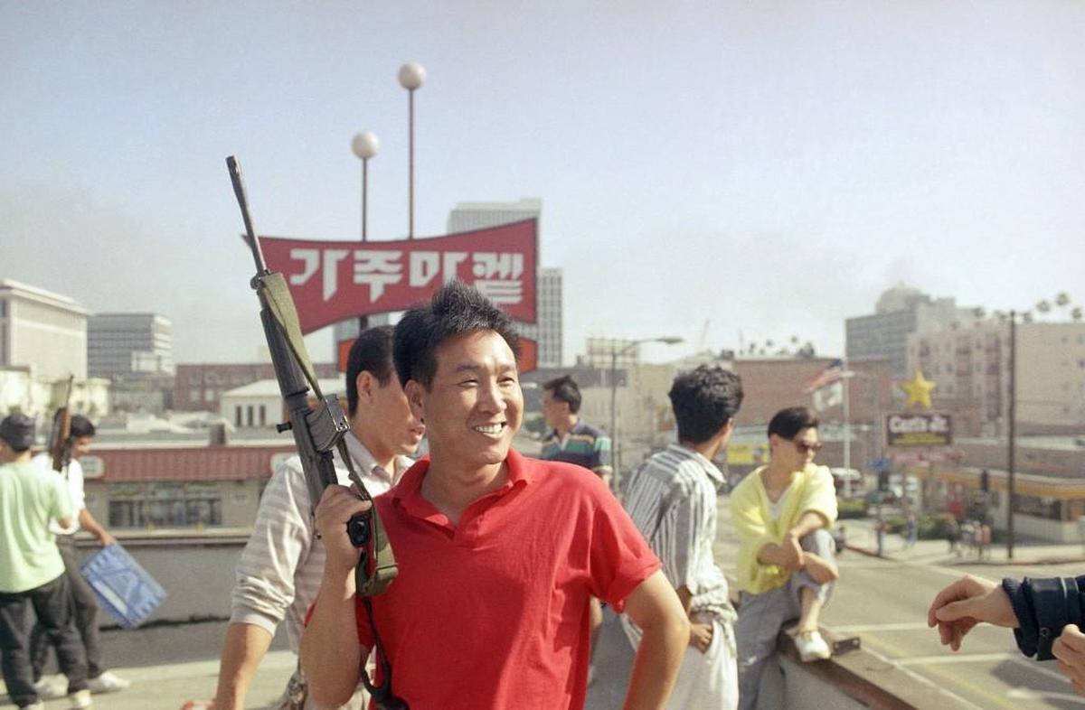 A Korean man carries an automatic weapon to prevent looters from entering a grocery store in Los Angeles, Thursday, April 30, 1992.