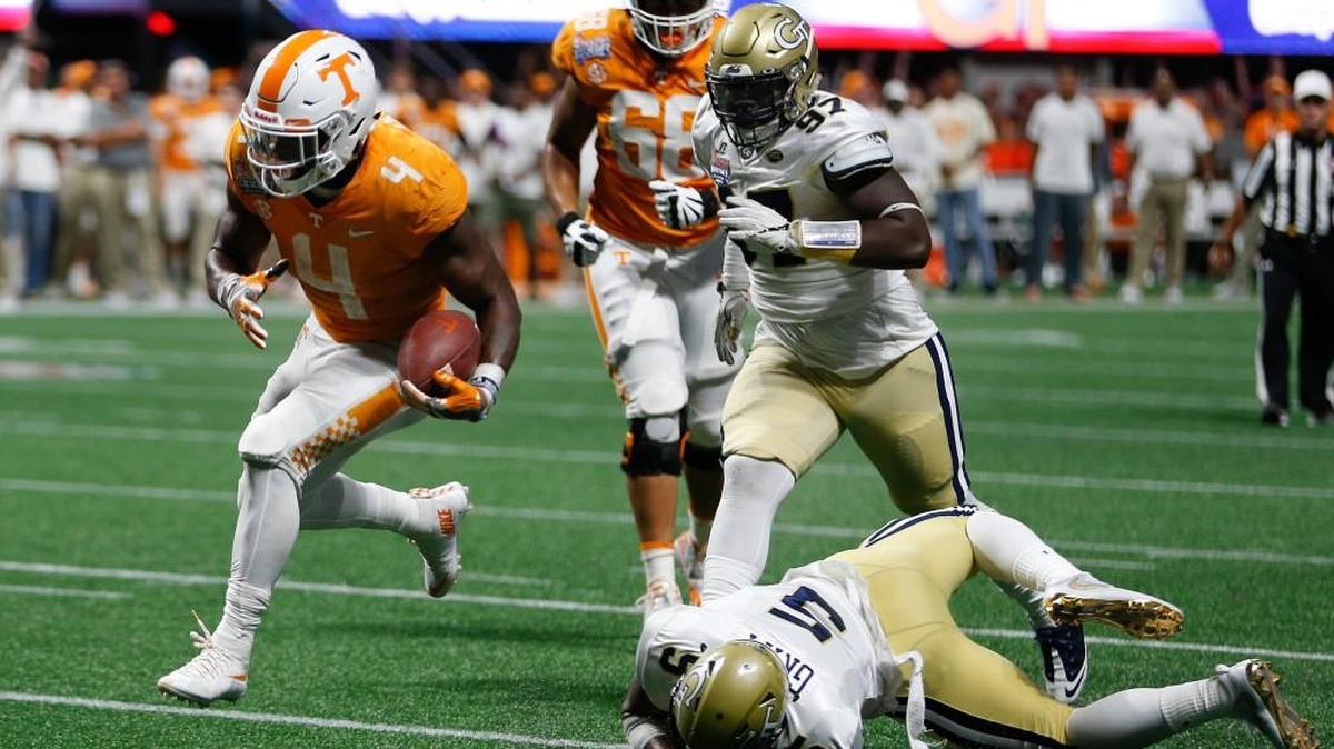 Tennessee running back John Kelly (4) runs past Georgia Tech defensive back A.J. Gray during Monday night’s game.