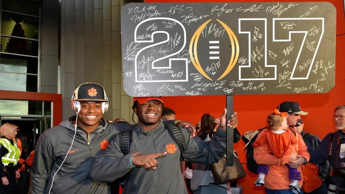 Clemson’s Jalen Williams, right, and K’Von Wallace hold a sign after returning Tuesday to Clemson, S.C., the day after the Tigers defeated Alabama 35-31 in the College Football Playoff championship NCAA college football game in Tampa.