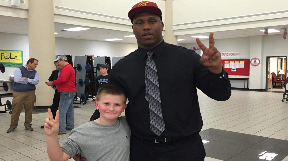 E.J. Price and 10-year-old fan Logan Sage pose for a photo after Price committed to USC over Georgia and Auburn. 