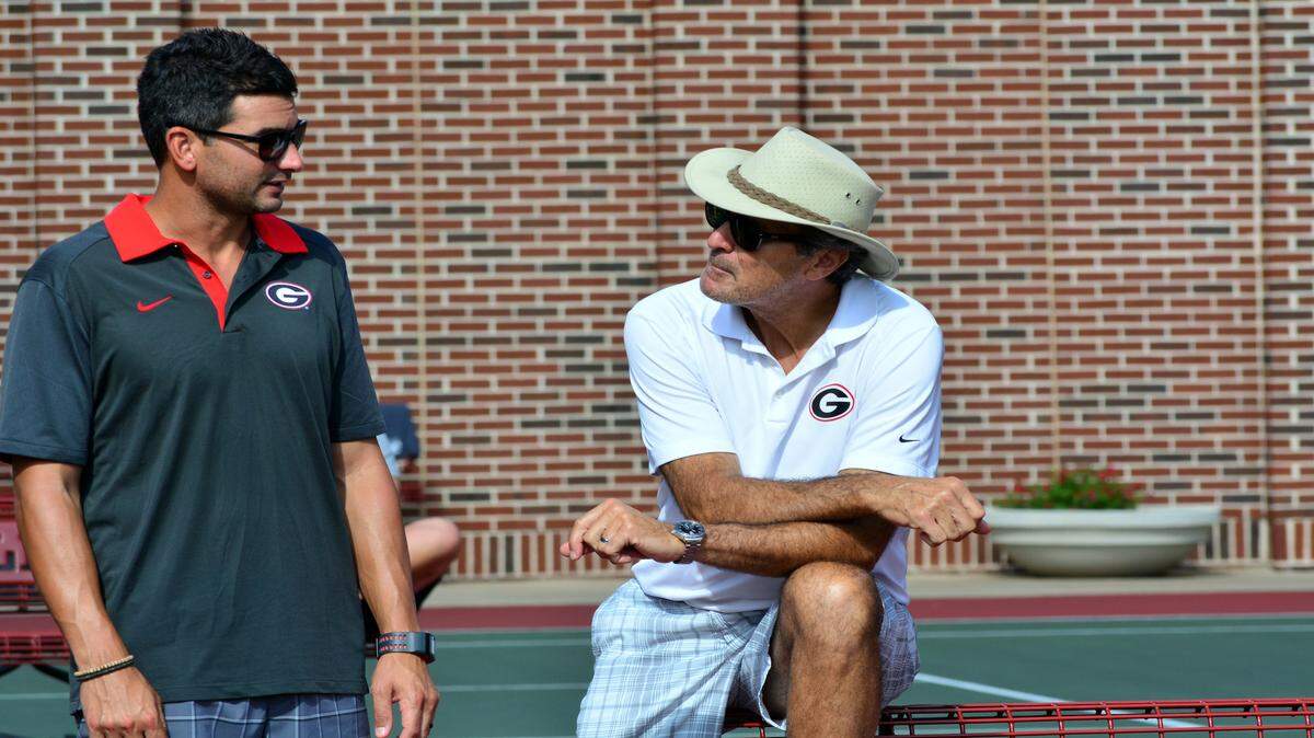 Former assistant Bo Hodge speaks with head coach Manny Diaz at a UGA tennis match. 
