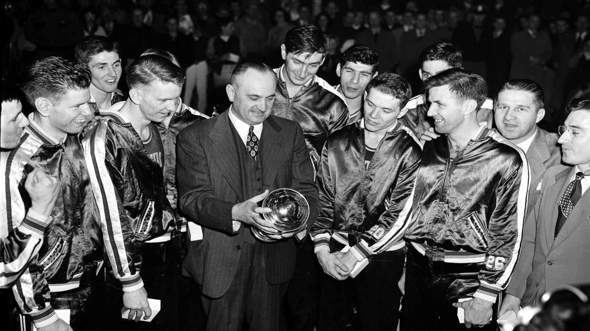 In this March 26, 1949, file photo, Kentucky basketball head coach Adolph Rupp and his team admire the NCAA basketball title cup after defeating Oklahoma A&M 46-36 in Seattle.