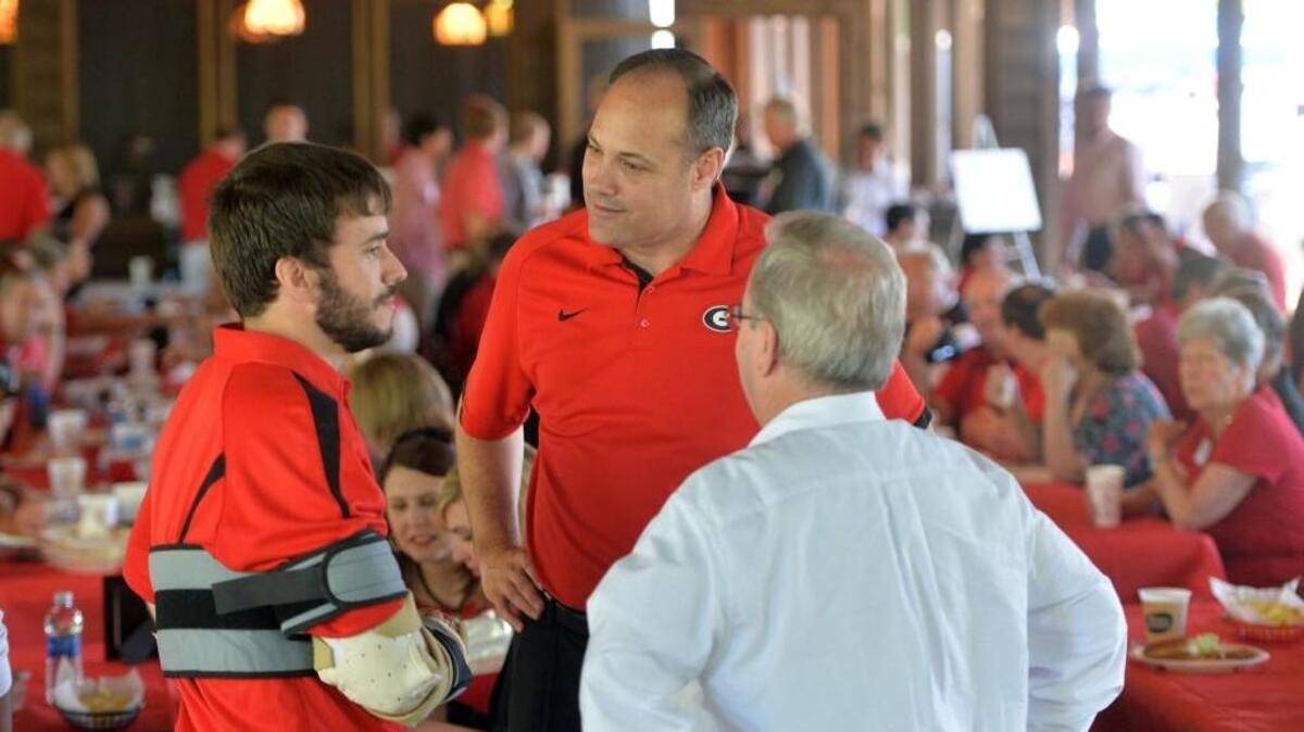 Georgia basketball coach Mark Fox (center) visits with David Thorpe (left) and his father Graham (right) during a barbecue for Georgia fans Wednesday at the Walnut Creek Shooting Preserve.