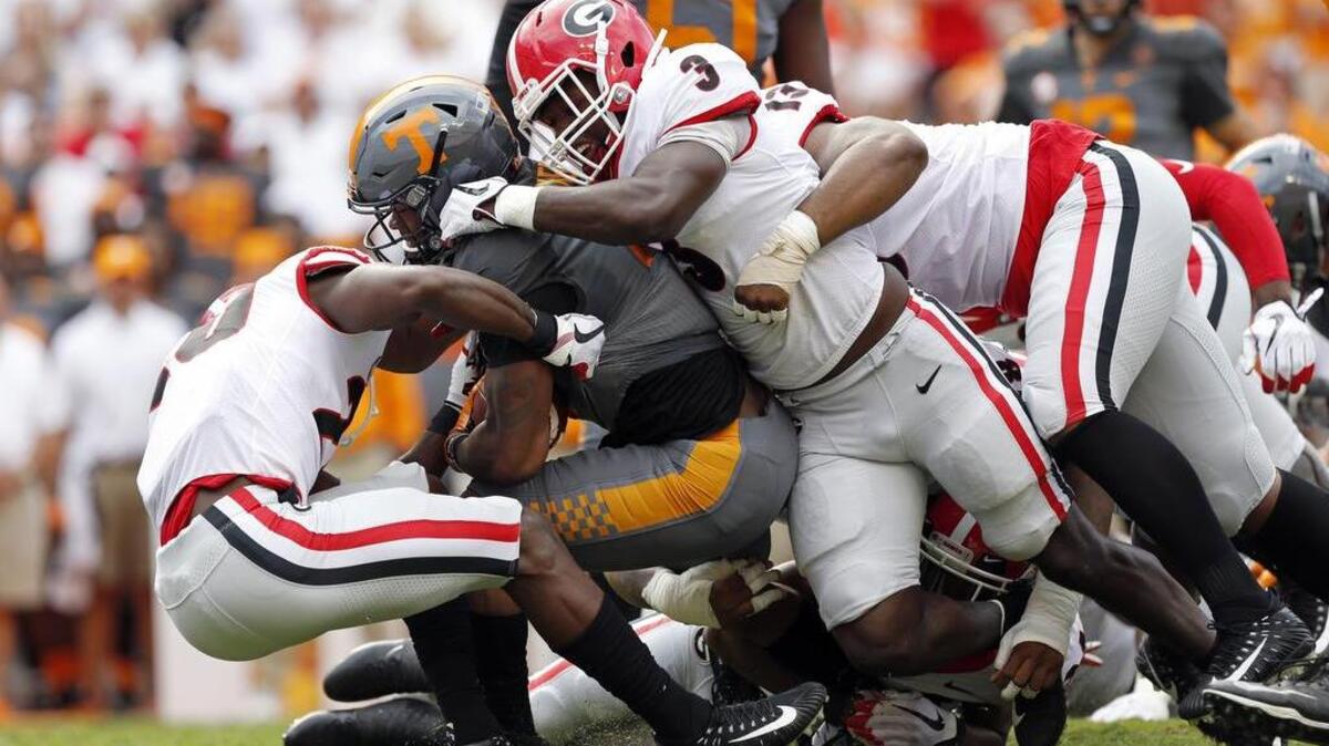 Tennessee running back John Kelly (4) is tackled by Georgia defensive back J.R. Reed (20) and linebacker Roquan Smith (3) during the first half of an NCAA college football game Saturday, Sept. 30, 2017, in Knoxville, Tenn. (AP Photo/Wade Payne)