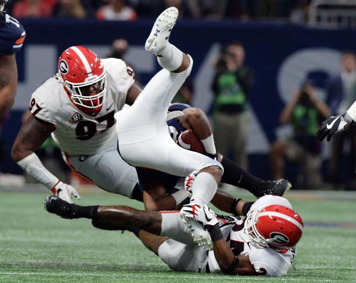 Georgia's John Atkins (97) and Dominick Sanders (24) upend Auburn's Kerryon Johnson (21) during first half action of the SEC Championship.