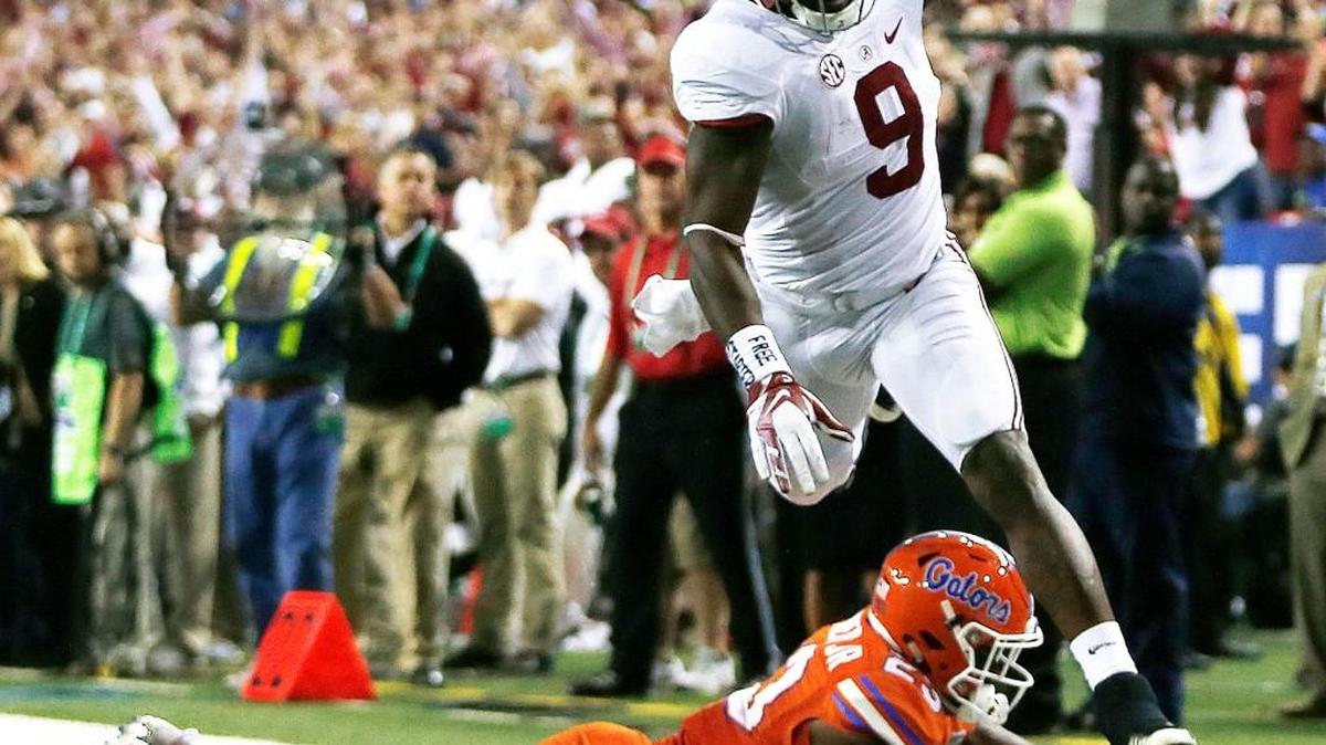 Alabama running back Bo Scarbrough (9) runs over Florida defensive back Chauncey Gardner during Saturday’s SEC title game.