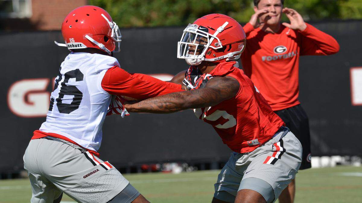 Cornerback Tyrique Mcghee (left) mixes it up in a drill with running back Brian Herrien (right) during Georgia's first preseason practice. 