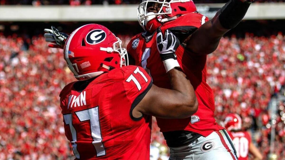 Isaiah Wynn, holding Sony Michel up after a score against Georgia Tech, could begin spring practice at left tackle or left guard.
