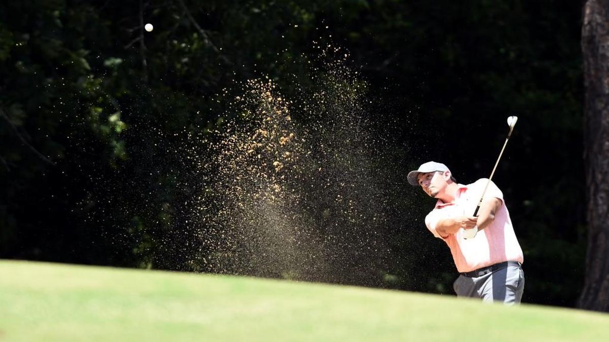 Adam Riley blasts out of a bunker onto the 17th green at Healy Point during Saturday’s first round of the Macon-Middle Georgia Championship.