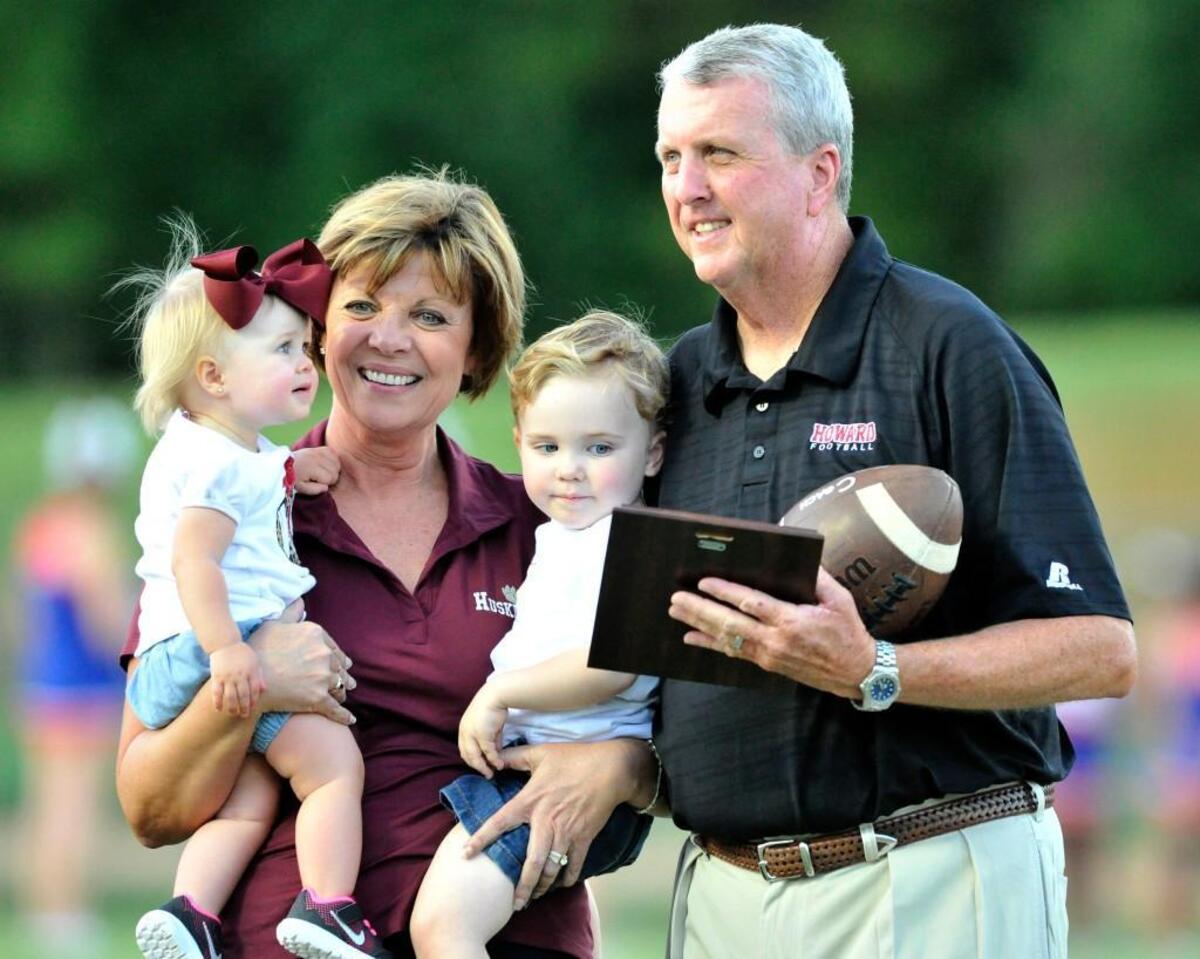 Howard's Barney Hester is greeted by his wife Lynn and their grandchildren at midfield Friday night after being presented a plaque and game ball by Howard principal Shannon Norfleet for his 500th game.