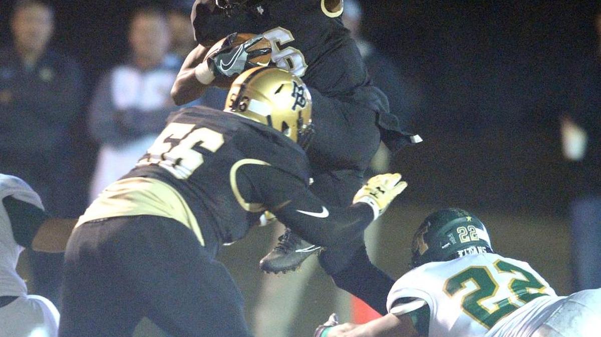 Mary Persons Bulldog Quen Wilson hurdles over a host of players Friday night against Blessed Trinity.