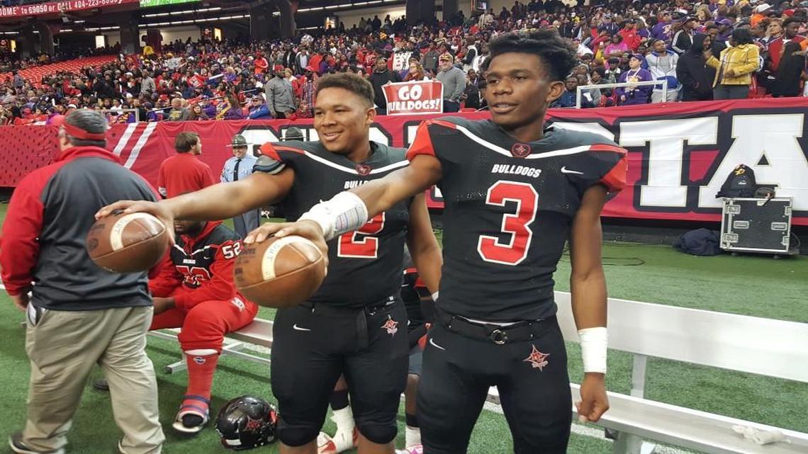 Macon County quarterback K'Hari Lane (2) and wide receiver Trey Brown pose for pictures in the closing moments of the Bulldogs’ GHSA Class 1A public championship victory Dec. 10 over McIntosh County Academy. Lane threw four touchdown passes, three to Brown, in setting the single-season state touchdown passing record.