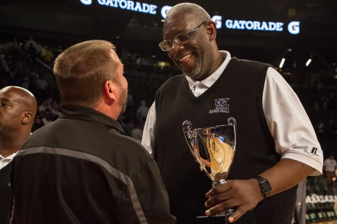 Upson-Lee boys basketball head coach Darrell Lockhart, the All-Middle Georgia Boys Basketball Coach of the Year, carries the championship trophy back to the locker room after winning the GHSA Class 4A final against St. Pius X.
