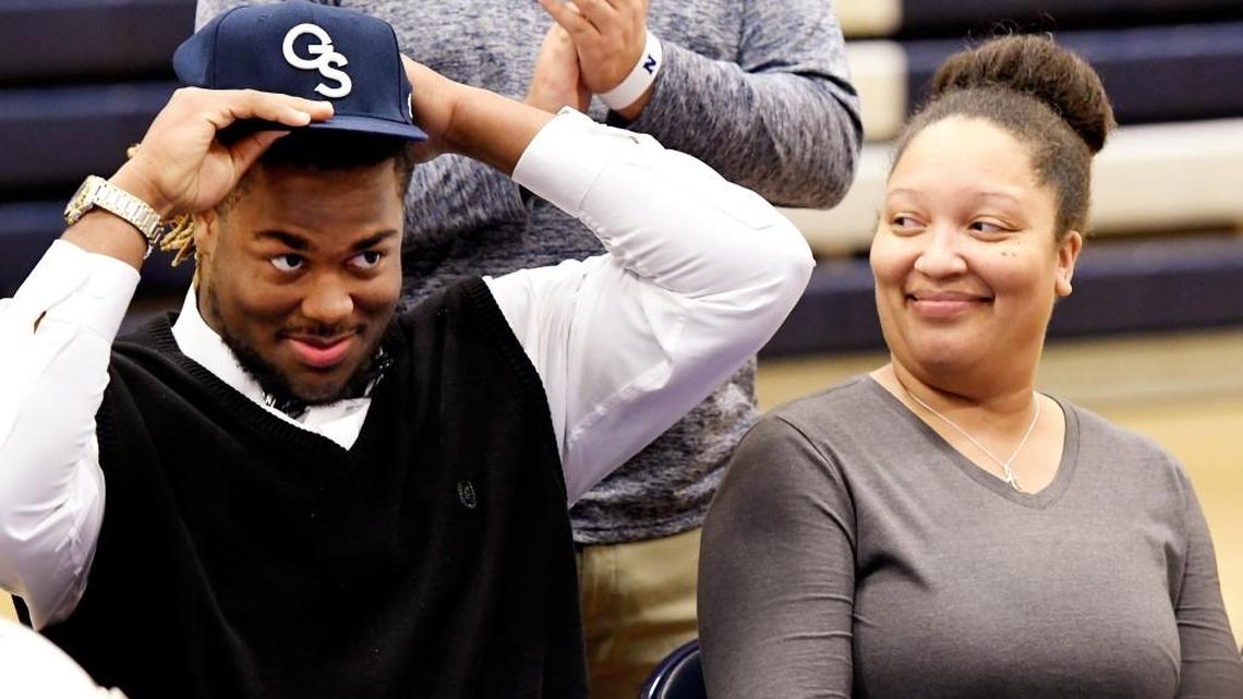 Northside offensive lineman Caleb Kelly places on a Georgia Southern hat while sitting next to his mother Harelyn Kelly-Wright during a National Signing Day ceremony in the school's gymnasium.