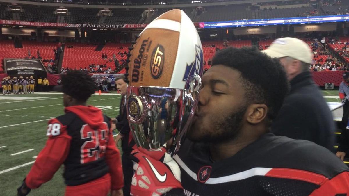 Macon County linebacker Kentarious Felton kisses the championship trophy following the Bulldogs' 35-0 victory Saturday, Dec.10, 2016 over McIntosh County Academy in the GHSA Class 1A public school championship at the Georgia Dome.