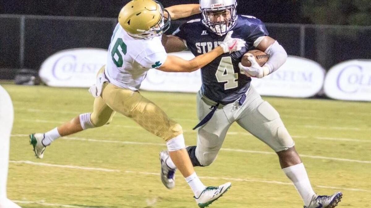 Stratford Academy’s Tyler Jordan (4) tries to avoid the tackle by Aquinas’s J.P. Lambert (16) during their game Friday night.