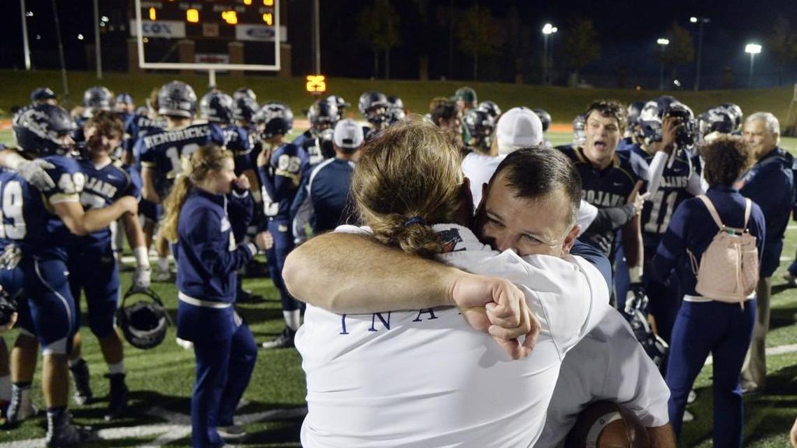 John Milledge Academy coach J. T. Wall, right, embraces a coach--and the game ball--after his team beat Gatewood, 17-0, to win the GISA Class 3A state championship.