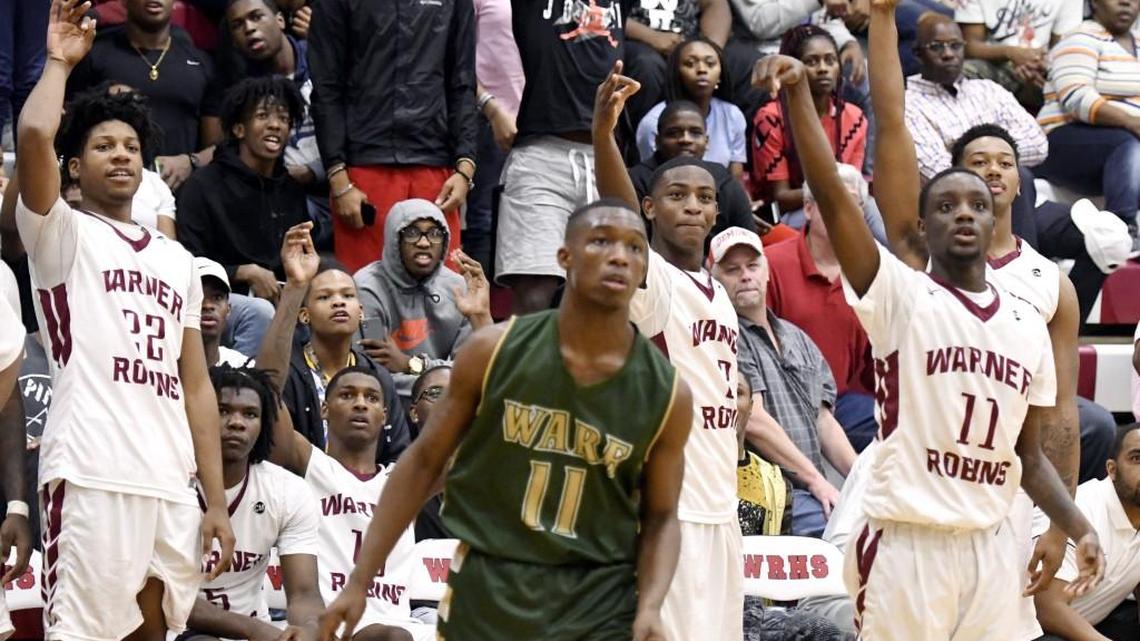 Warner Robins players stand up on the bench as guard Doug Duvall (11) puts up a 3-point shot Feb. 18 during the Demons' 96-63 win over Ware County in their GHSA 5A first round playoff game.