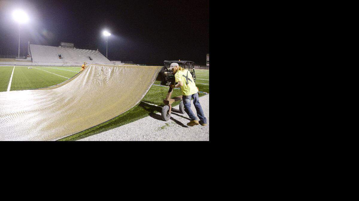  A crew with Deluxe Athletics out of Marietta rolls out the last section of artificial turf along the home sideline of McConnell-Talbert Stadium the night of July 17, 2015.