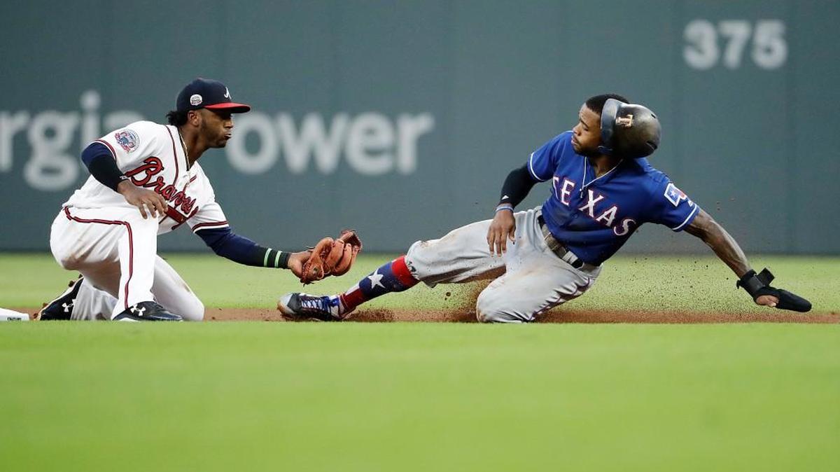 Atlanta’s Ozzie Albies, left, tags out Texas’ Delino DeShields at second base.