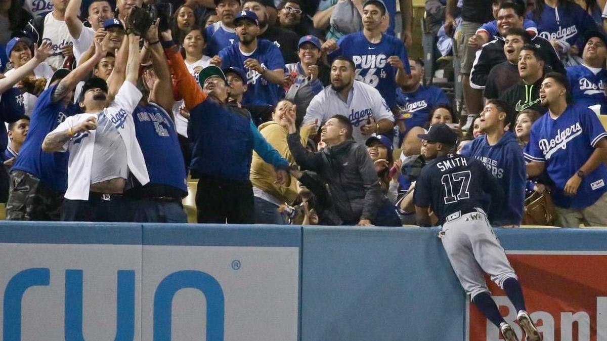 Fans reach a home run ball hit by Los Angeles’ Corey Seager as Atlanta Braves center fielder Mallex Smith looks on during the eighth inning the teams’ game Friday.