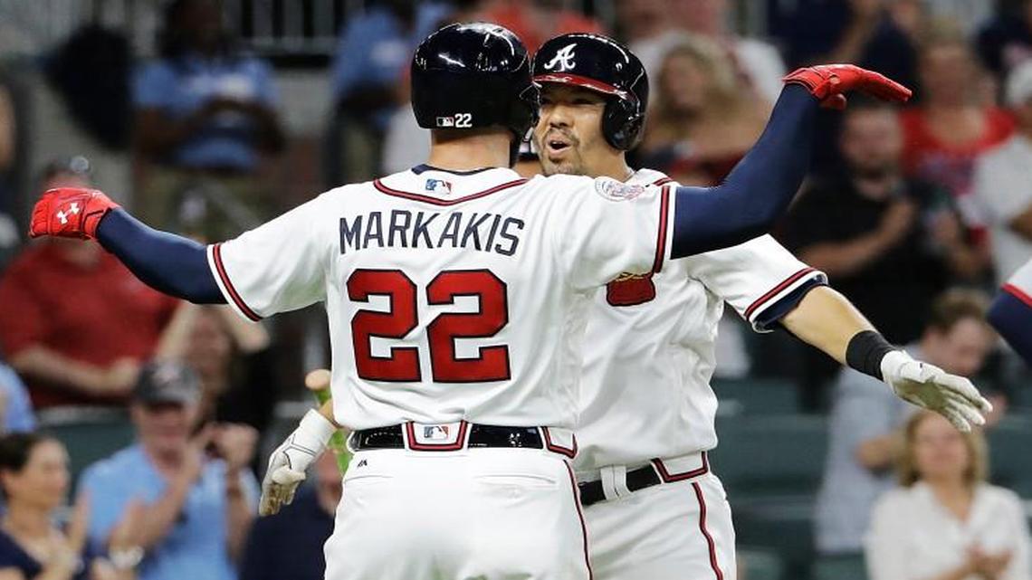 Atlanta Braves' Kurt Suzuki, center, high-fives teammate Nick Markakis after they scored off Suzuki's two-run home run as Washington Nationals catcher Matt Wieters stands at right in the eighth inning of a baseball game in Atlanta, Friday, May 19, 2017. Atlanta won 7-4.