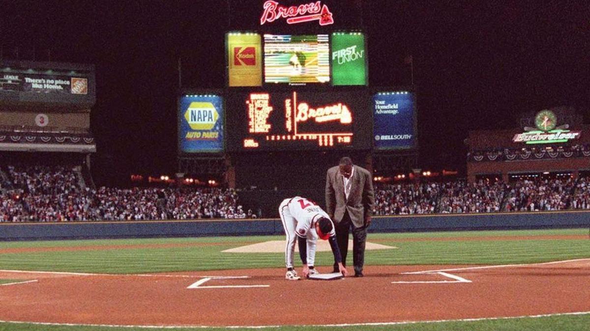 In this April 4, 1997, file photo, former Atlanta Braves great Hank Aaron looks on as pitcher Tom Glavine places down home plate from Atlanta Fulton County Stadium on top of the plate at Turner Field before the Braves opened their new home against the Chicago Cub in Atlanta. Turner Field began its brief life as the main stadium for the 1996 Summer Olympics. After just two decades as the home of the Atlanta Braves, it's headed for another transformation. The Braves are moving to the suburbs next season, leaving the Ted to Georgia State University.