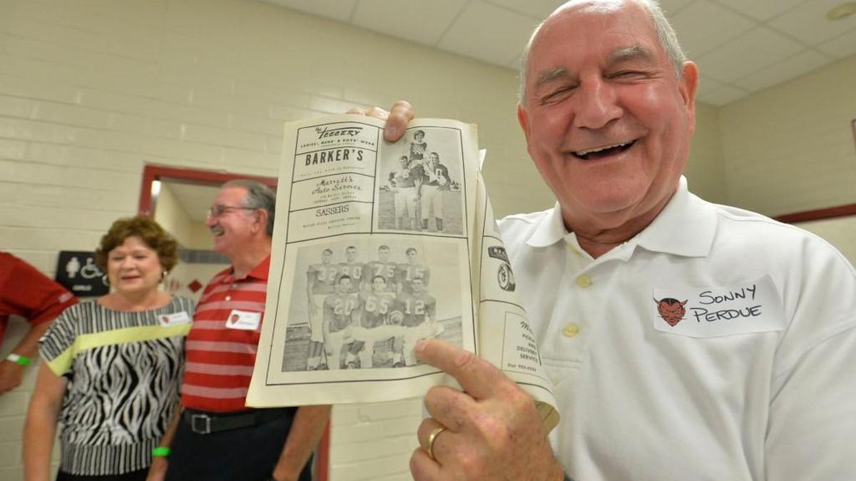 Sarah and Van Herrington, left, brought a program from the 1965 season to share with the team’s quarterback, a guy with a good arm, Sonny Perdue, who was quick to point out his old No. 12 Demons jersey.