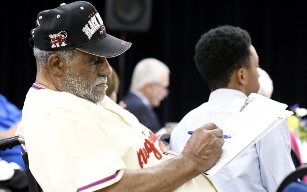 Macon Sports Hall of Fame inductee Robert Scott signs a program during the induction ceremony inside the Macon Coliseum's Monument Room Thursday night.