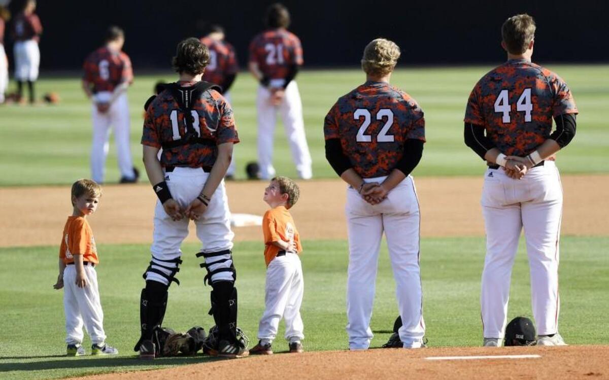 Youth baseball players flank Mercer's Charlie Madden (18) during the Nation Anthem on Thursday.