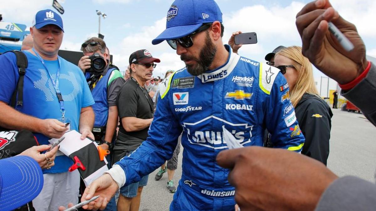 Jimmie Johnson center, signs autographs during practice for Sunday's NASCAR Daytona 500 auto race at Daytona International Speedway in Daytona Beach, Fla.