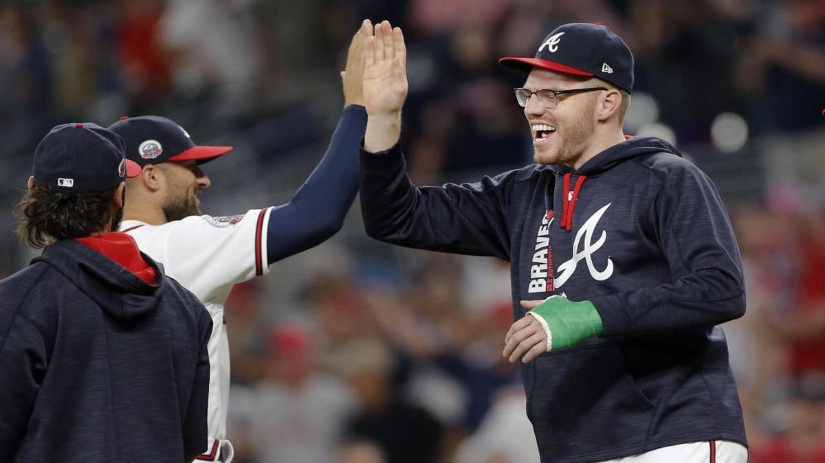 Injured Atlanta Braves first baseman Freddie Freeman, right, celebrates with right fielder Nick Markakis after the final out of the team’s win over Philadelphia in early June.