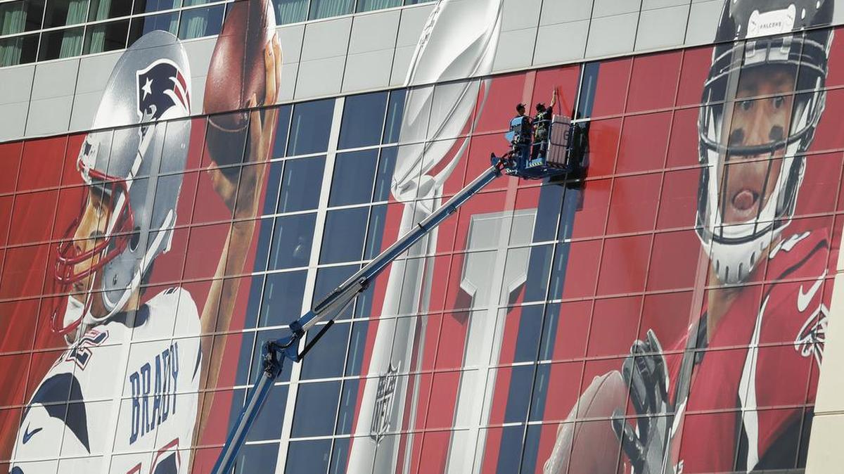 Workers attach a sign to the front of NRG Stadium as preparations continue for the NFL Super Bowl 51 football game Sunday, Jan. 29, 2017, in Houston.