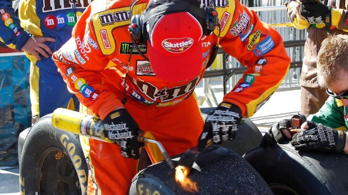 A race crew member for Kyle Busch uses a blow torch to clean debris off a tire during Sunday’s race at Phoenix International Raceway.