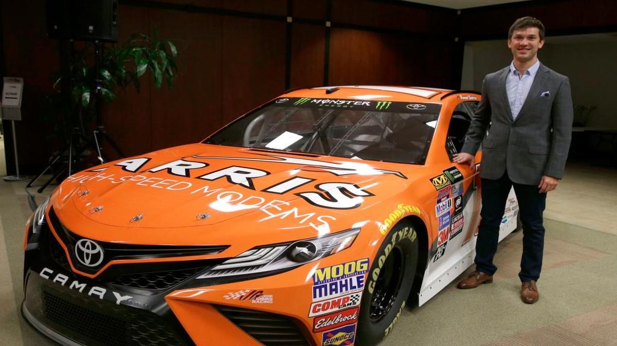 Driver Daniel Suarez poses for a photo with the NASCAR Cup Series race car he will drive this season during a news conference at Joe Gibbs Racing in Huntersville, N.C., Wednesday, Jan. 11, 2017.